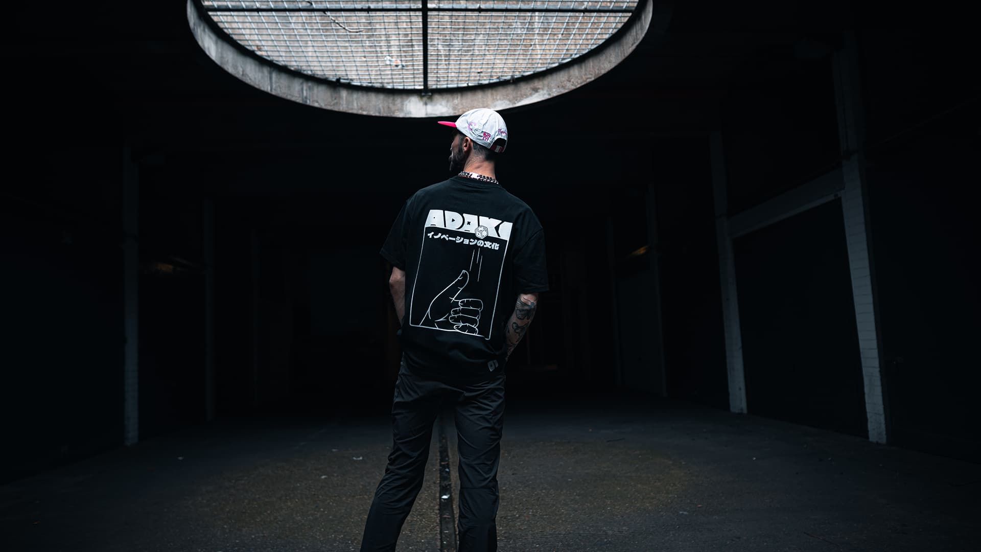 A photograph of a man in an Adaki shirt in an underground car park