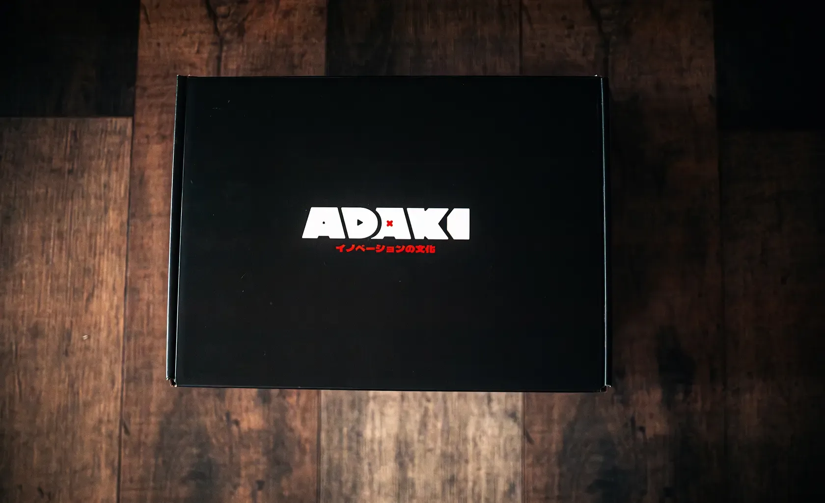 A photo of the Adaki box closed, showing the top graphic with the Adaki logo