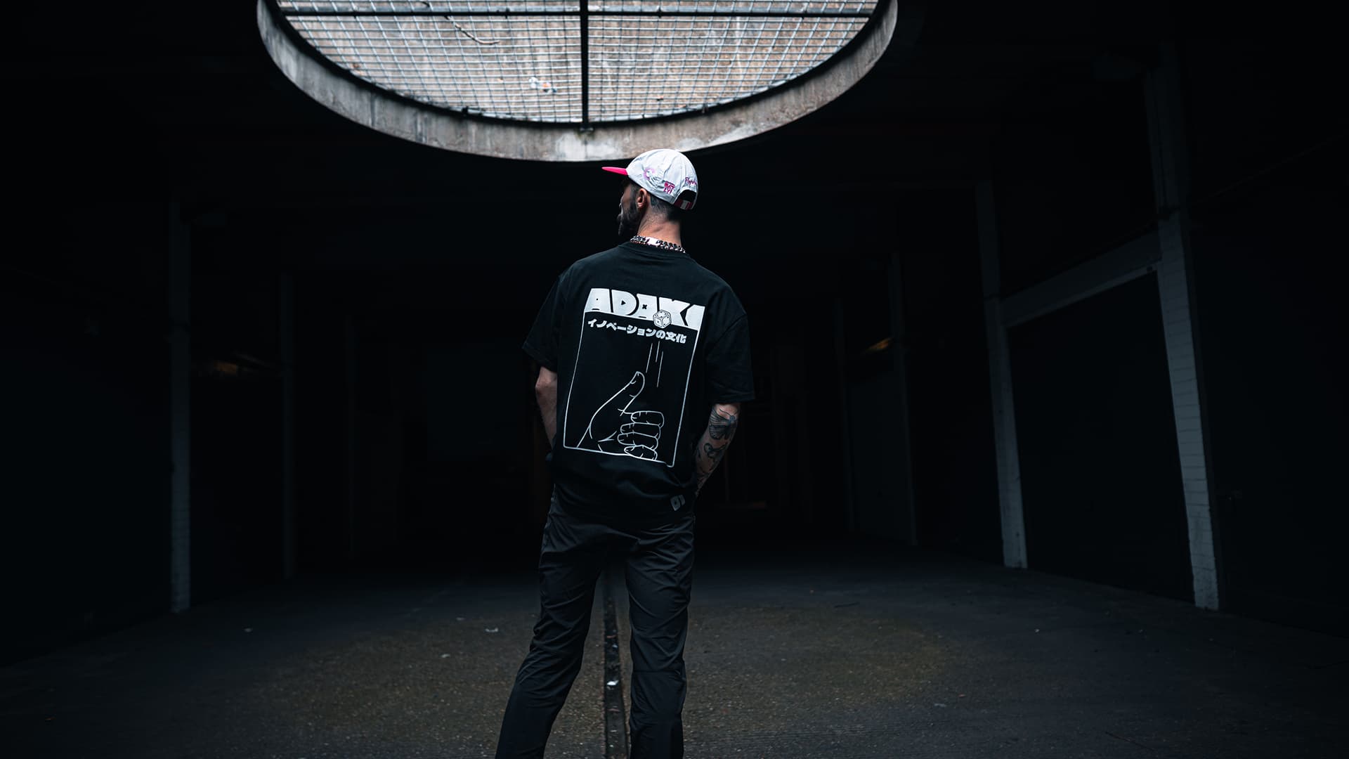 A photograph of a man in an Adaki shirt in an underground car park