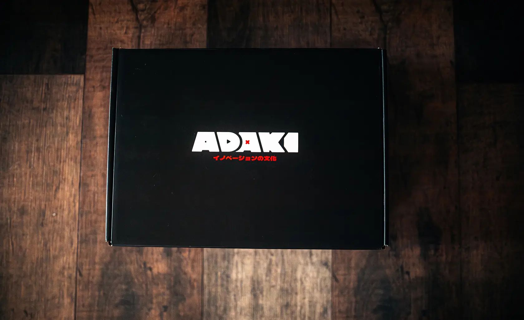 A photo of the Adaki box closed, showing the top graphic with the Adaki logo