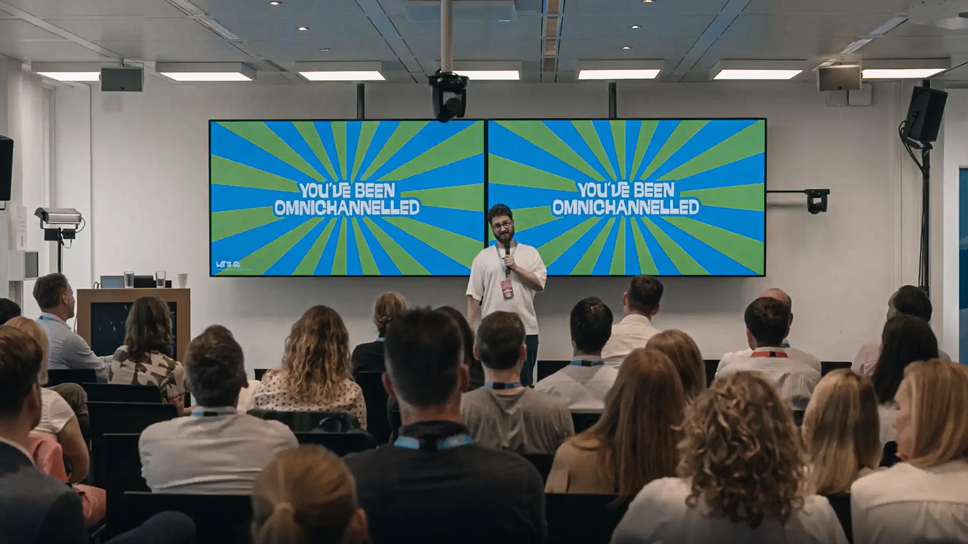 An image of James standing in front of an audience presenting with a slide behind him saying 'you've been omnichannelled